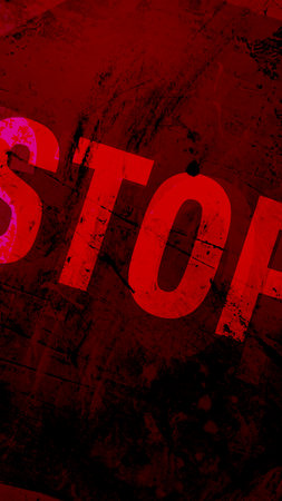 A stop sign is written in red on a grunge background. The sign is surrounded by a red and black textureの写真素材