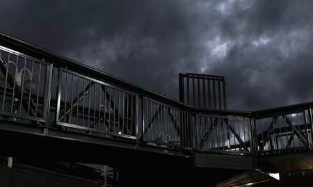A bridge with a railing and a dark sky. The sky is overcast with storm clouds, giving an ominous...