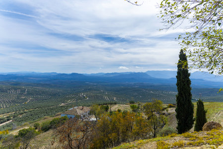 A beautiful mountain view with a house in the distance. The distant valley is covered by fields of olive trees. Hills of Ubeda viewの写真素材