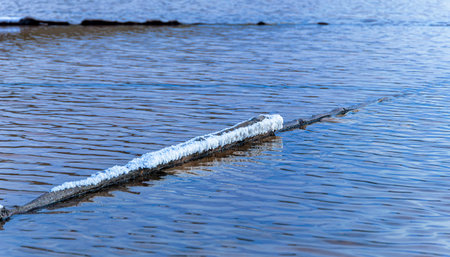Salt formations accumulate on an elongated structure that floats on the water of a salt flat. The water is calm and blueの写真素材