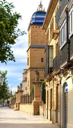 A street with a building with a blue dome on top. The building is brown and has a lot of statues on itの写真素材