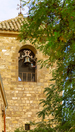 A bell tower with a bell hanging from it. The tower is made of stoneの写真素材