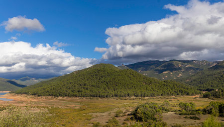 A mountain range with a cloudy sky in the background. The sky is blue and the clouds are whiteの写真素材