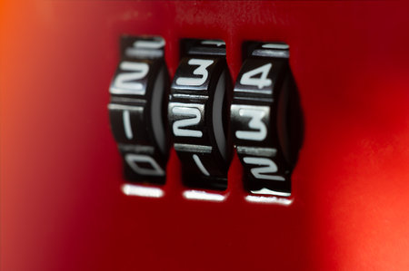 Extreme close-up of the rotating numerical wheels of a black combination lock set to "123" against a vibrant red background, symbolizing security, access, and digital protectionの写真素材