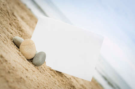Blank white sign on a sand beach with stones and pebblesの写真素材