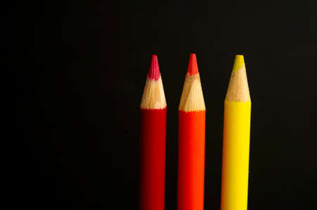 red orange and yellow pencil crayons on a black の写真素材