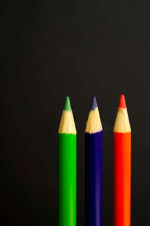 green, purple and red pencil crayons on a black の写真素材