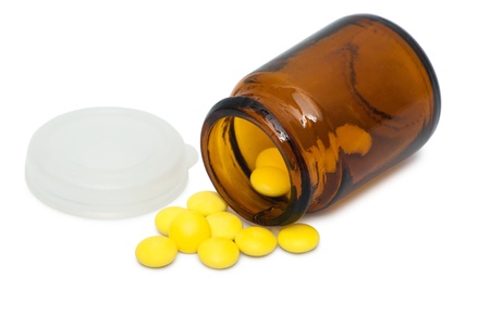 Glass bottle with yellow tablets isolated on white backgroundの写真素材