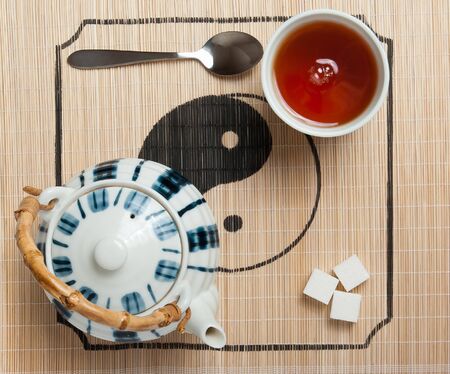 Teapot and cup, sugar, spoon on the matの写真素材