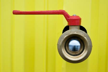 Closed water supply valve with a red handle in the droplets of waterの写真素材