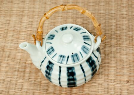 porcelain teapot with bamboo handles on the matの写真素材