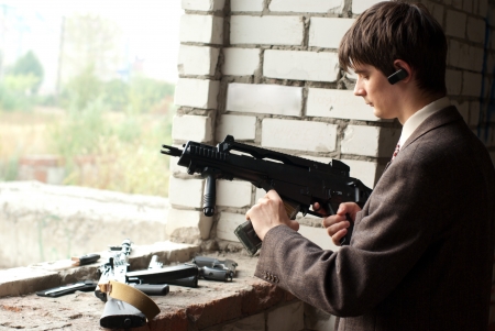 young man in unfinished building with submachine gunの写真素材
