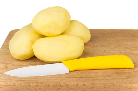 Heap of peeled raw potatoes and ceramic knife isolated on white backgroundの写真素材