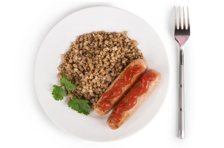 Grilled Sausage with tomato ketchup, boiled buckwheat and parsley in plate on white. Top viewの写真素材