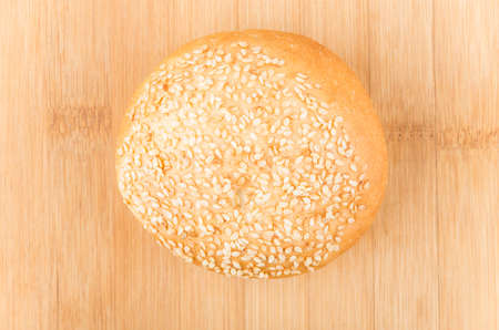 Appetizing bun sprinkled with sesame seeds on bamboo board