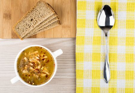 Pea soup, bread and spoon on table