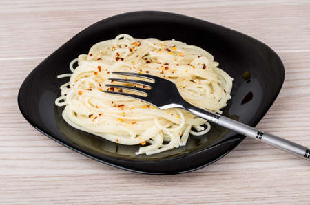 Spaghetti sprinkled with spices in black glass plate on tableの写真素材