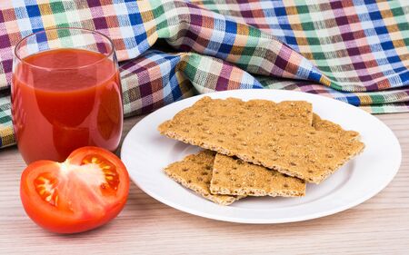 Wheat crisp bread tomato and juice in glass on wooden tableの写真素材