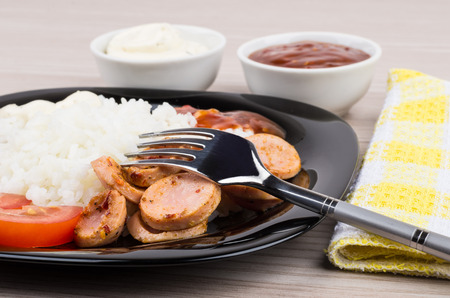 Close up of plate with rice sausage tomatoes ketchup mayonnaise bowls with sauceの写真素材