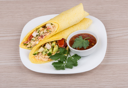 Two Shawarma with chicken and parsley in white plate bowl with ketchup on wooden tableの写真素材