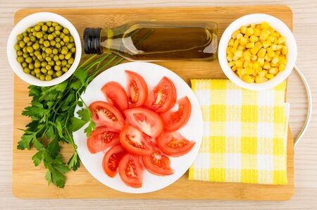 Tomatoes, green peas, sweet corn, parsley and olive oil on board, top viewの写真素材
