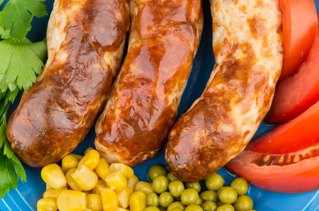 Background with fried sausage, green peas, sweet corn and slices of tomatoesの写真素材