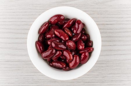 Red canned white beans in glass bowl on wooden table, top viewの写真素材