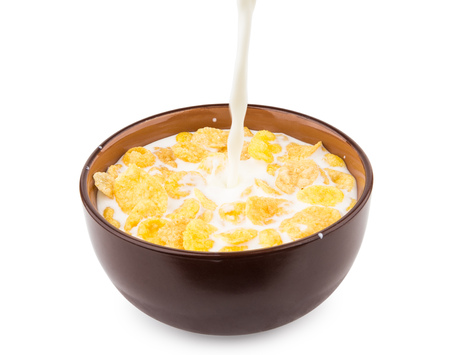 Pouring milk in bowl of corn flakes isolated on white background
