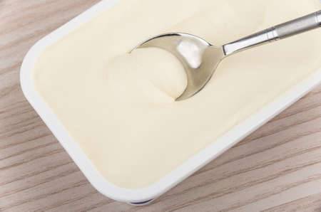 Melted cheese in box and spoon on wooden tableの写真素材