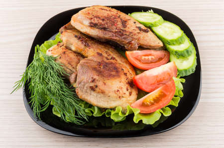 Slices of roast pork with salad, tomatoes, cucumbers in glass plate on tableの写真素材