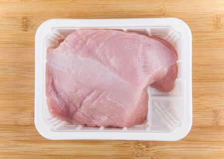 Fillet of Turkey breast in plastic box on board, top viewの写真素材