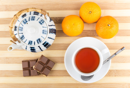 Cup of tea, tangerines, teapot and chocolate pieces with hazelnuts on table, top viewの写真素材