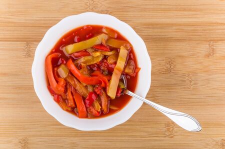 Lecho of bell pepper in glass bowl on bamboo table, top viewの写真素材