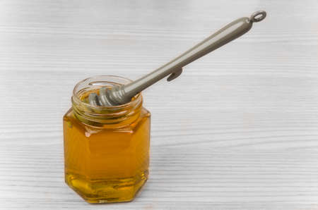 Transparent jar of honey with  stick on wooden tableの写真素材