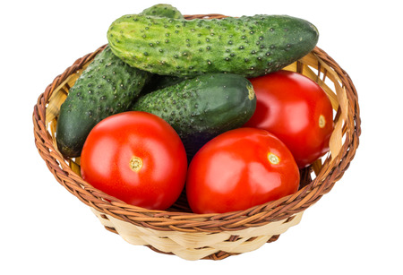 Tomatoes and cucumbers in wicker basket isolated on white backgroundの写真素材