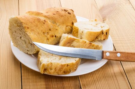 Pieces of baguette in glass plate and knife on wooden tableの写真素材