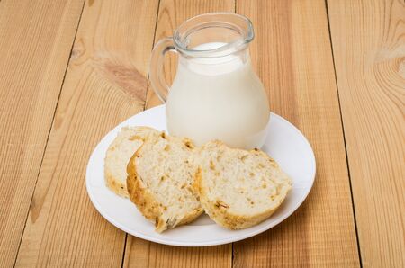 Three slices of bread and jug milk in glass plate on wooden tableの写真素材