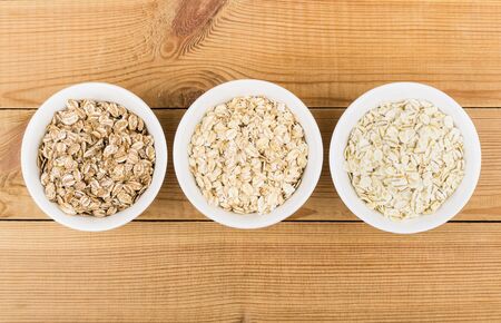 Row glass bowl with oat, rye, barley flakes on wooden table. Top viewの写真素材
