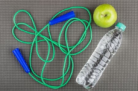 Jump rope, green apple and bottle of water on grey mat. Top viewの写真素材