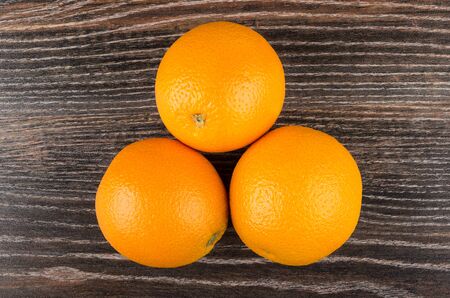 Three ripe oranges on dark wooden table. Top viewの写真素材
