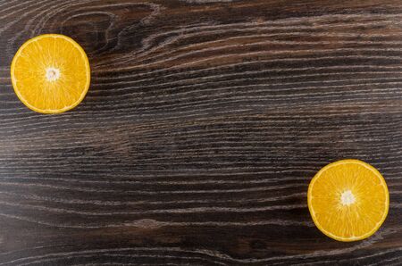 Two half of ripe oranges in corners on dark wooden table. Top viewの写真素材