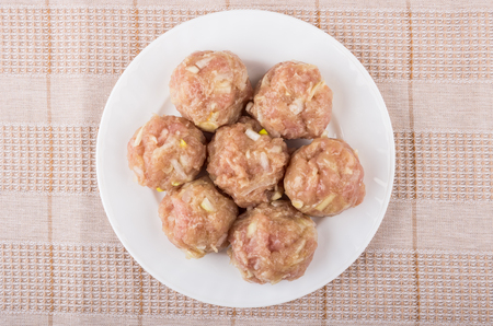 Raw meatballs in white plate on pink tablecloth. Top viewの写真素材