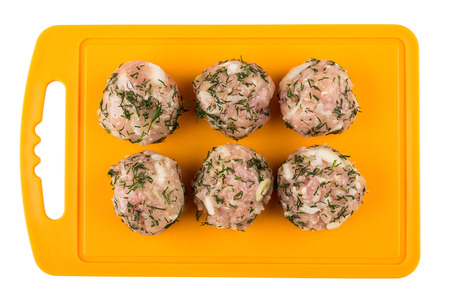 Raw meatballs with dill on orange cutting board isolated on white background. Top viewの写真素材