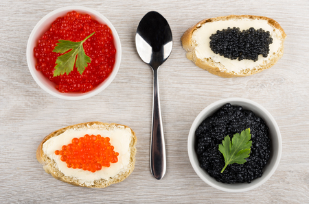 Imitation red and black caviar in bowls, sandwiches with butter on wooden table. Top viewの写真素材