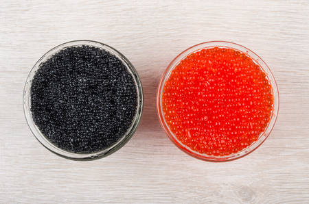 Imitation red and black caviar from seaweed in transparent bowls on wooden table. Top viewの写真素材