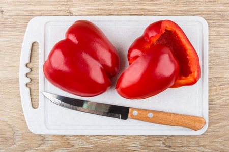 Pieces of sweet pepper and kitchen knife on plastic cutting board on wooden table. Top viewの写真素材