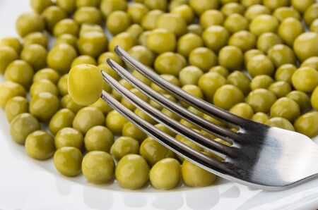Green peas and fork in white plate close upの写真素材