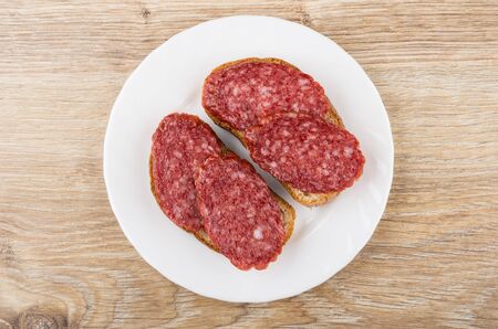 Two sandwiches wit smoked sausage in plate on wooden table. Top viewの写真素材