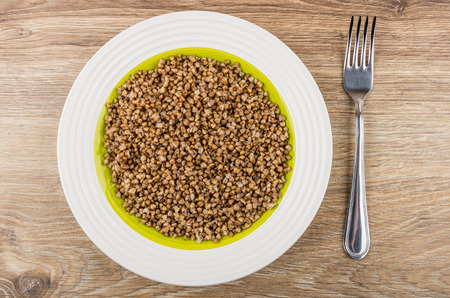 Prepared buckwheat in glass plate and fork on wooden table. Top viewの写真素材