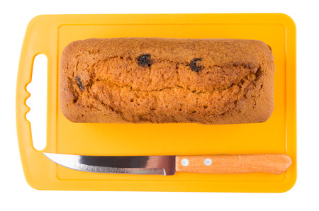Muffin loaf with raisin and knife on orange cutting board isolated on white background. Top view